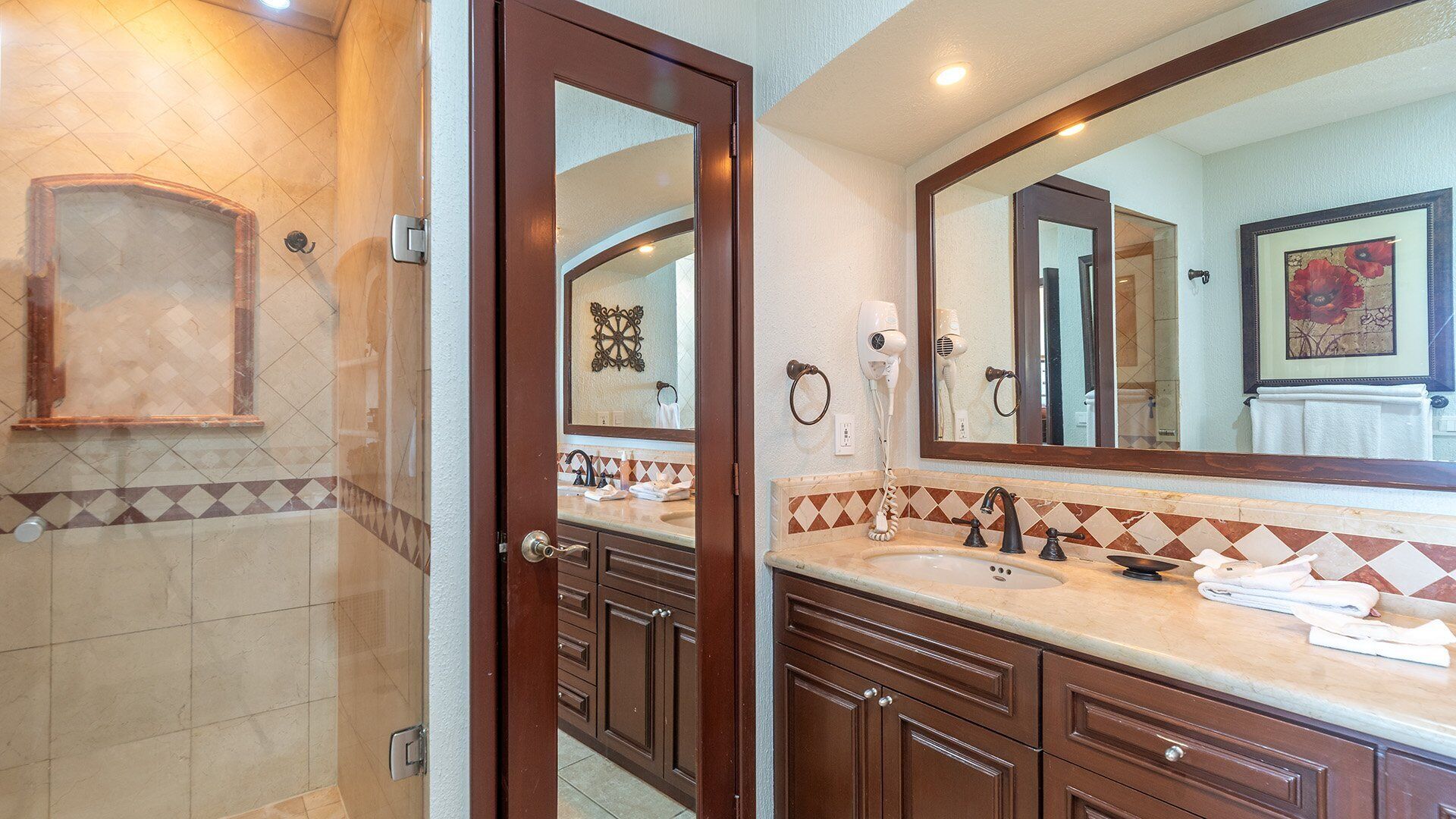 A bathroom with a large mirror, two sinks, a shower area, and a towel rack.