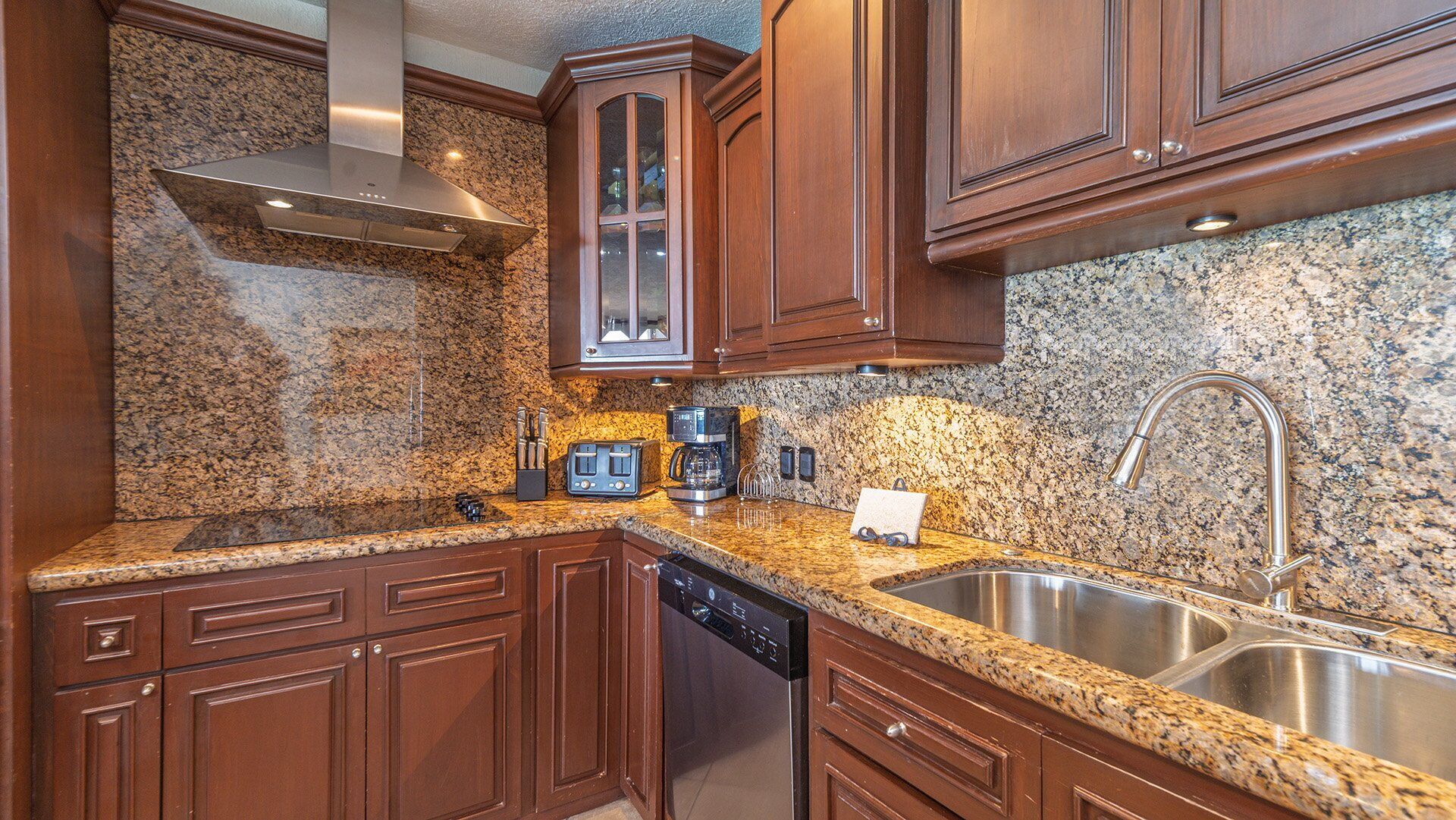 A kitchen with granite countertops, stainless steel appliances, and wooden cabinetry.
