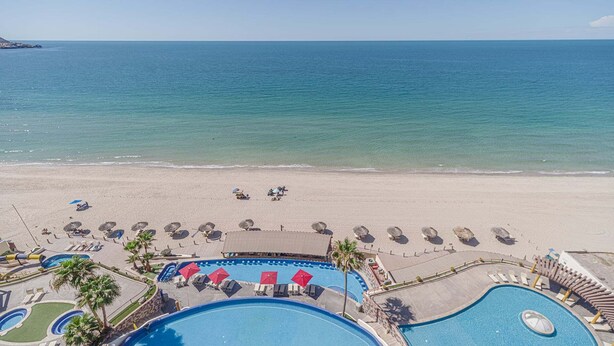 A resort with a swimming pool, beach area, and ocean view.