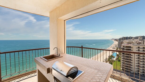 Un balcone con lavandino, barbecue e vista sull'oceano e sulla spiaggia.