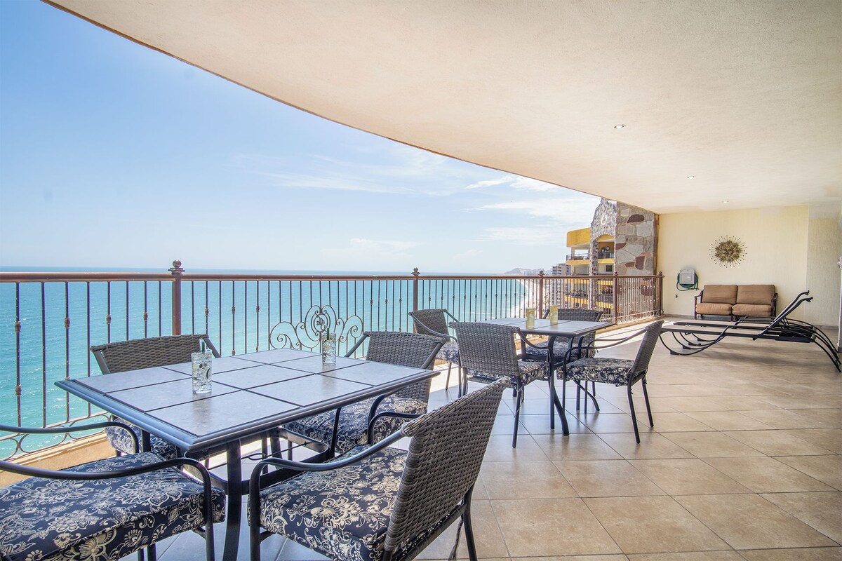 Un balcon avec une table et des chaises, un canapé et une vue sur l’océan.