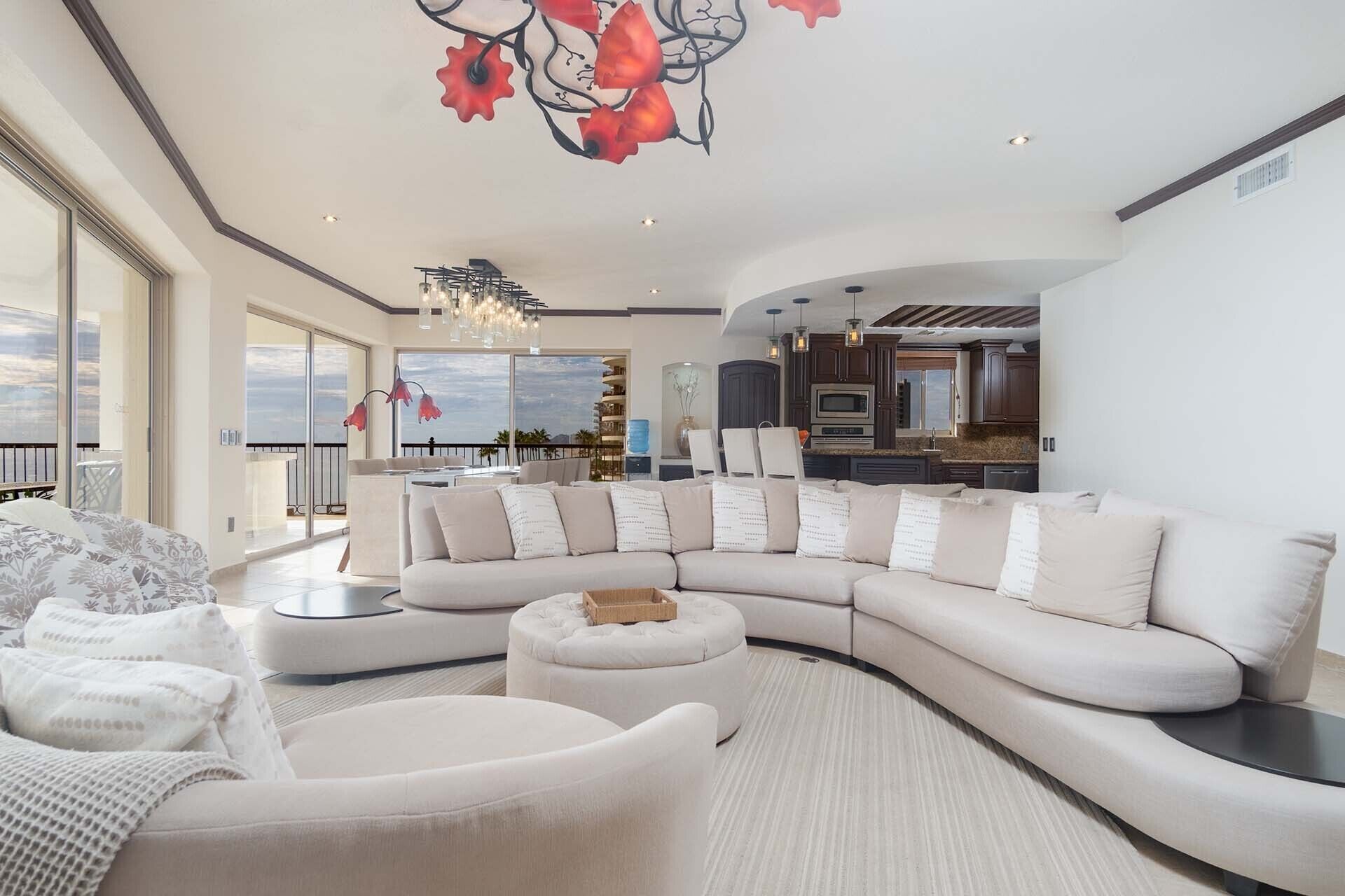Un salon spacieux avec un grand canapé d’angle, un pouf rond et un coin repas offrant une vue agréable.