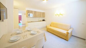 A modern living room with a dining area, a sofa, and a kitchen with a microwave. - DolceVita Apartments N. 521 (Venice)