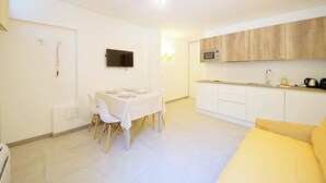 A compact living space with a dining area, kitchenette, and a yellow sofa. - DolceVita Apartments N. 521 (Venice)