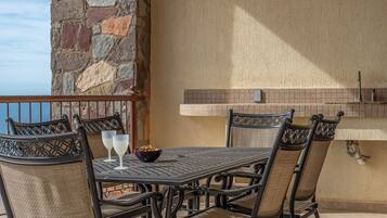 A patio with a stone wall, a tiled backsplash, and a metal table with wicker chairs.