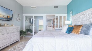 Une chambre avec un grand lit, une commode, un miroir et une vue sur la salle de bain.
