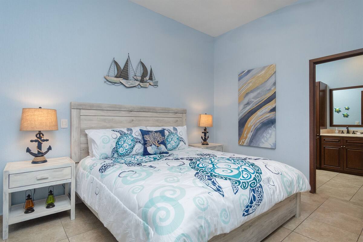 Een slaapkamer met een bed, nachtkastjes en een badkamer.