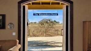 Een open deur naar een veranda met een bord waarop staat 'The Winemakers Porch'.