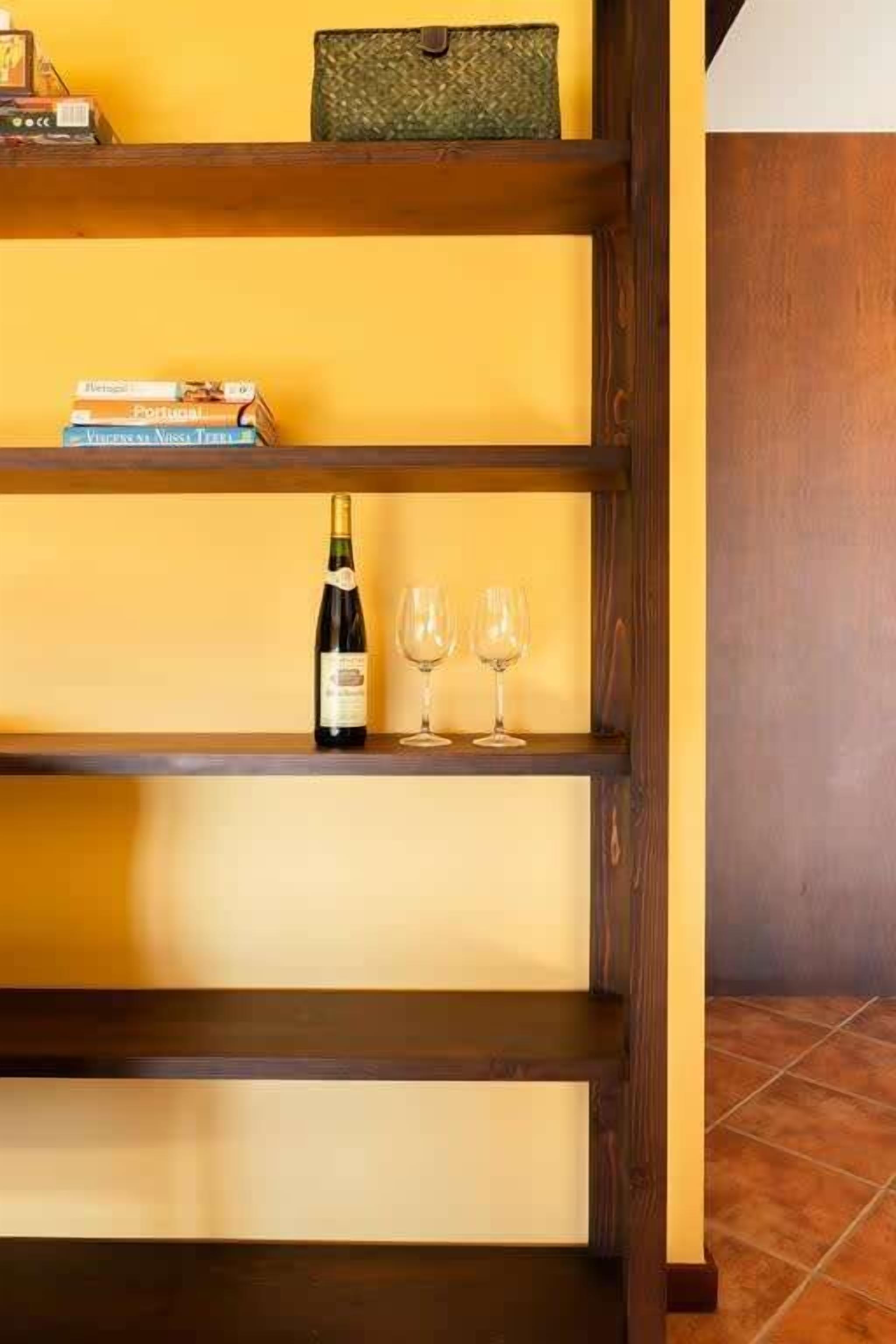 Een houten boekenkast met boeken en een fles wijn.