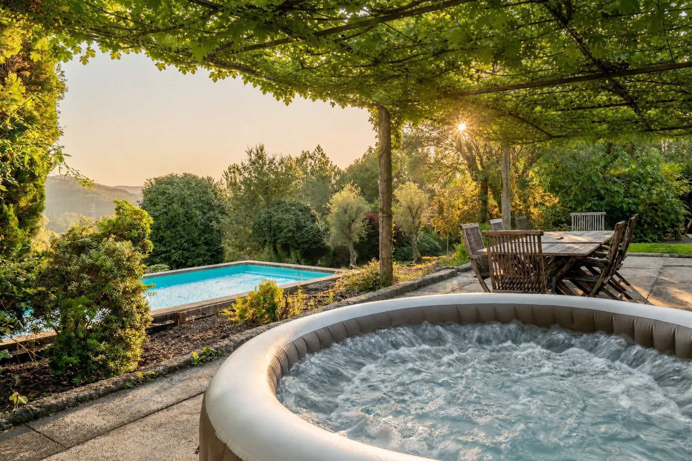 A hot tub surrounded by a garden with a pool and wooden furniture.