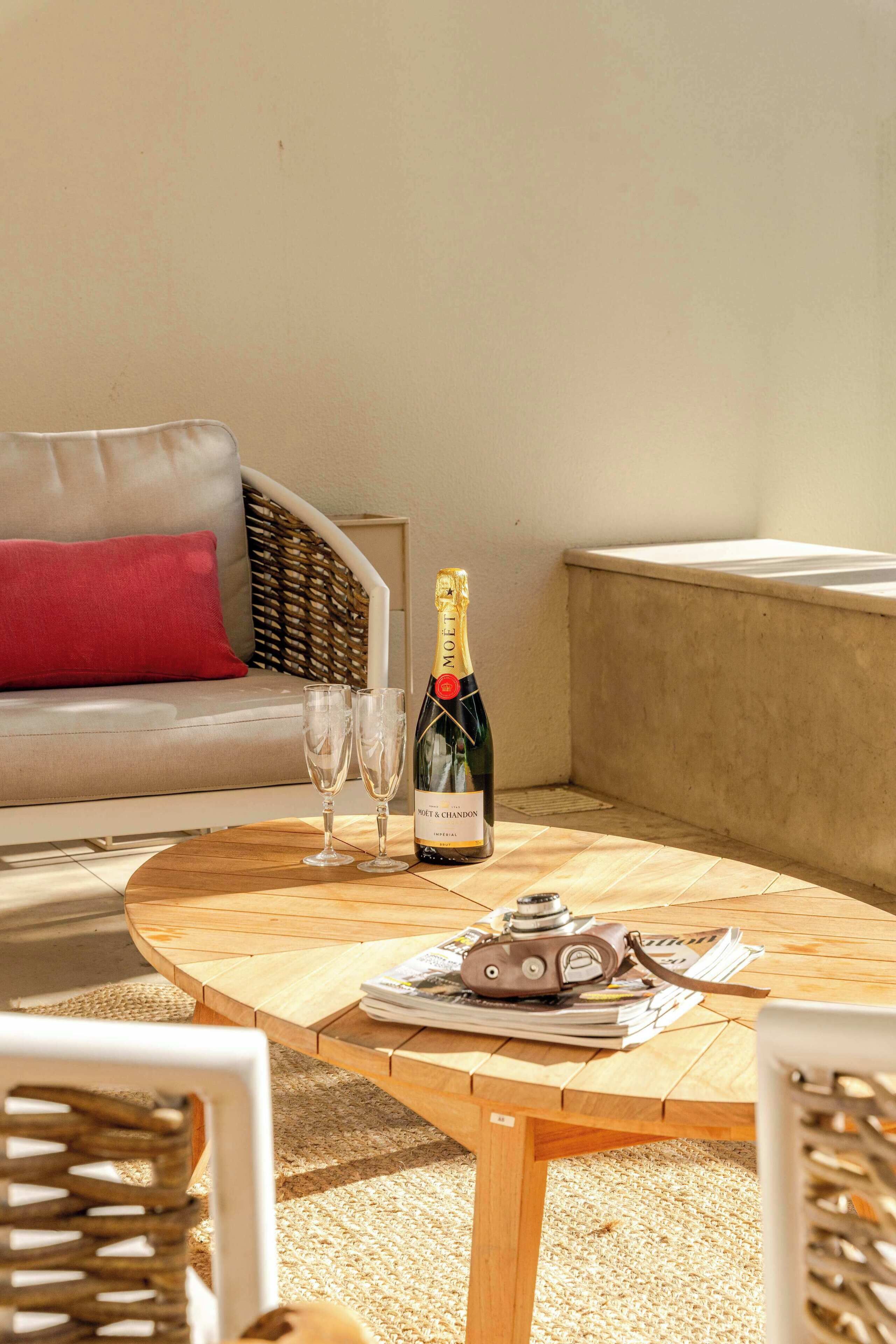 Ein runder Holztisch mit einer Moët & Chandon Champagnerflasche, zwei Gläsern und einer Kamera auf einem Magazin.
