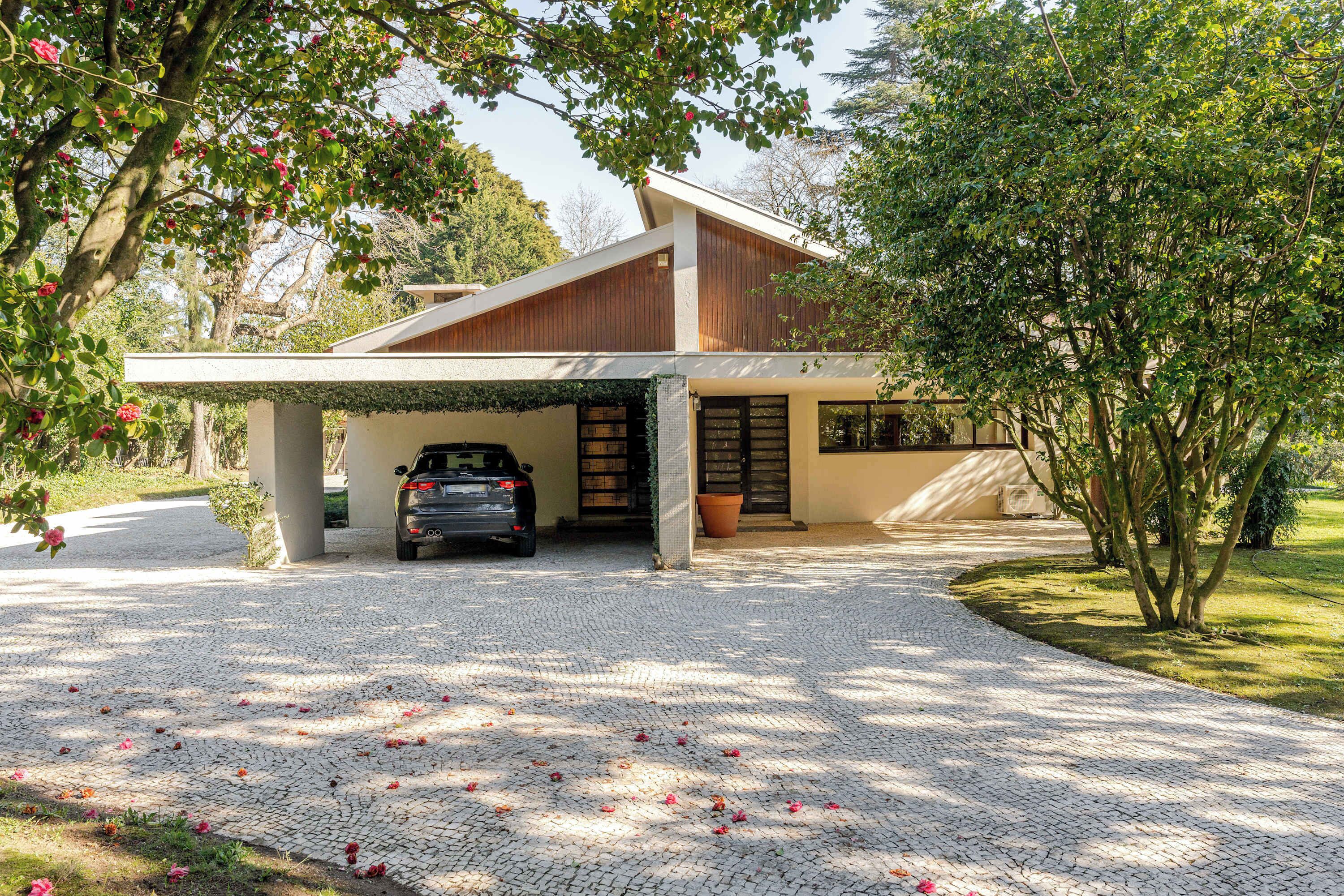Ein modernes Haus mit überdachter Garage, befestigter Auffahrt und einem Baum mit rosa Blüten.
