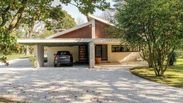 A modern house with a covered garage, a paved driveway, and a tree with pink flowers.