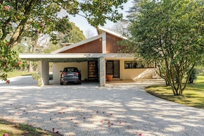 A modern house with a covered garage, a paved driveway, and a tree with pink flowers.