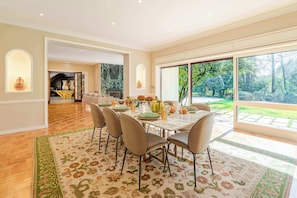 A dining area with a table set for four, a fireplace, and a view of a garden through large windows.