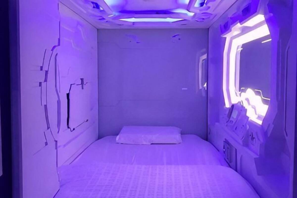 A room with a bed, a window, and a control panel on the wall.