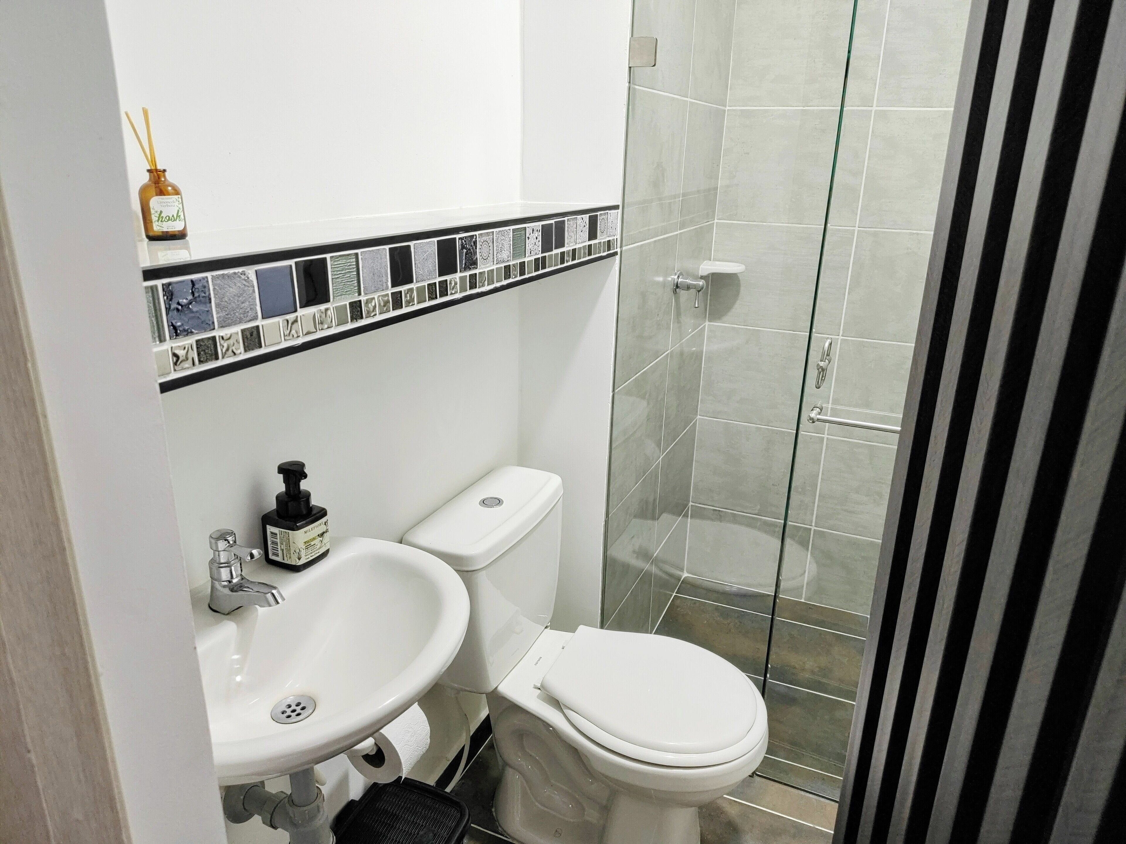 Un baño con lavamanos blanco, inodoro y cabina de ducha de vidrio.