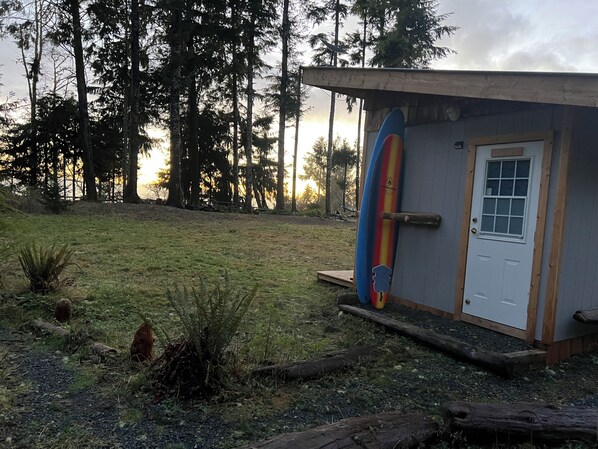 A small building with a door and a surfboard leaning against it.