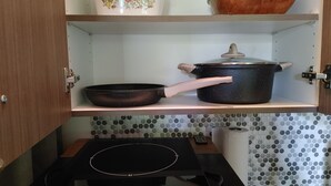 A kitchen with a stove, a frying pan, a pot, and a bowl on the shelf. - Spruce Suite - Beach and Vineyard steps away! (Cobble Hill)