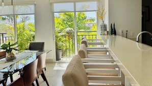 Cozinha moderna com uma ilha grande, armários brancos e vista para vegetação exuberante.