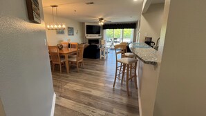 Una cocina moderna con encimera de granito, mesa de comedor de madera y taburetes de bar.