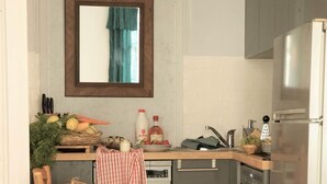 Una cocina compacta con una silla de madera, un lavamanos pequeño, un refrigerador y piso de baldosas.