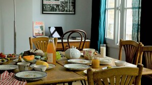 Una mesa de comedor dispuesta con platos, una tetera, una jarrón y un bol.