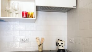 A kitchen with a modern stove, a cutting board, and a pot holder. - Rosa House (Positano)