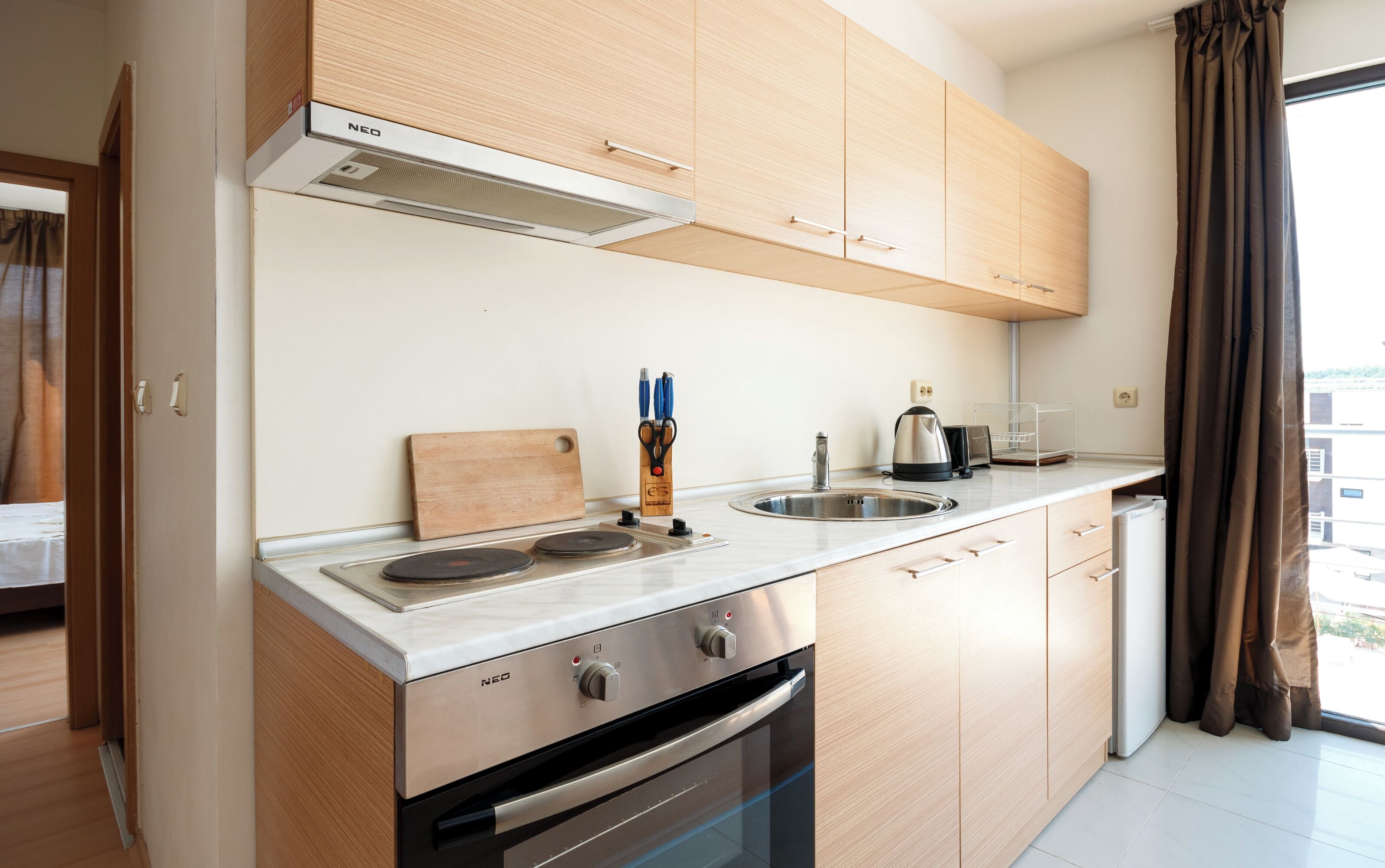 Eine moderne Küche mit Holzausstattung, einer Edelstahlspüle und einem eingebauten Backofen.