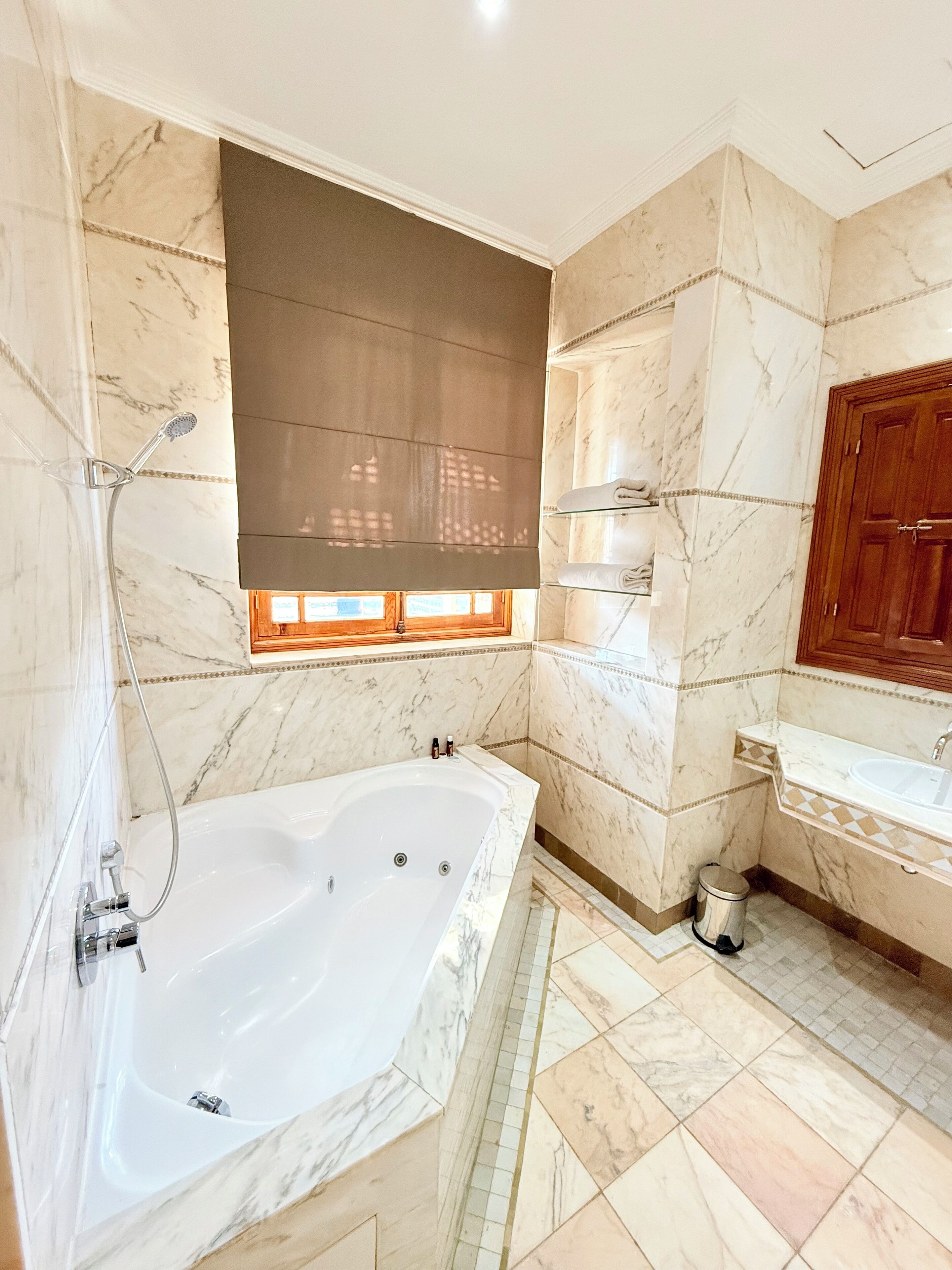A bathroom with a large bathtub, a shower, a sink, and a wooden cabinet.
