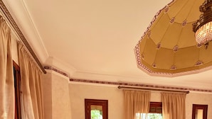 A spacious bedroom with a large bed, a fireplace, two armchairs, and a chandelier. - VILLA 34 - 4 Masters, Moroccan Charm & Modern Comfort with Private Pool (Marrakech)