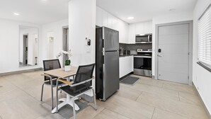 Eine moderne Küche mit weißen Schränken, einem schwarzen Kühlschrank und einer Mikrowelle.