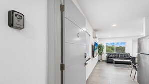 Eine moderne Küche mit integriertem Kühlschrank, ein Essbereich mit Sofa und Tisch sowie ein großes Fenster mit Blick ins Freie.