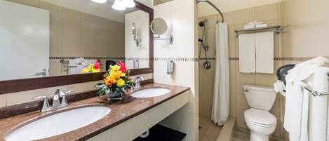 A bathroom with two sinks, a shower, and a toilet.