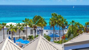 A hotel with a view of the ocean, palm trees, and a sailboat in the distance. - La Vista Hotel (Simpson Bay)