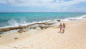 A sandy beach with rocky outcrops and a clear view of the ocean.