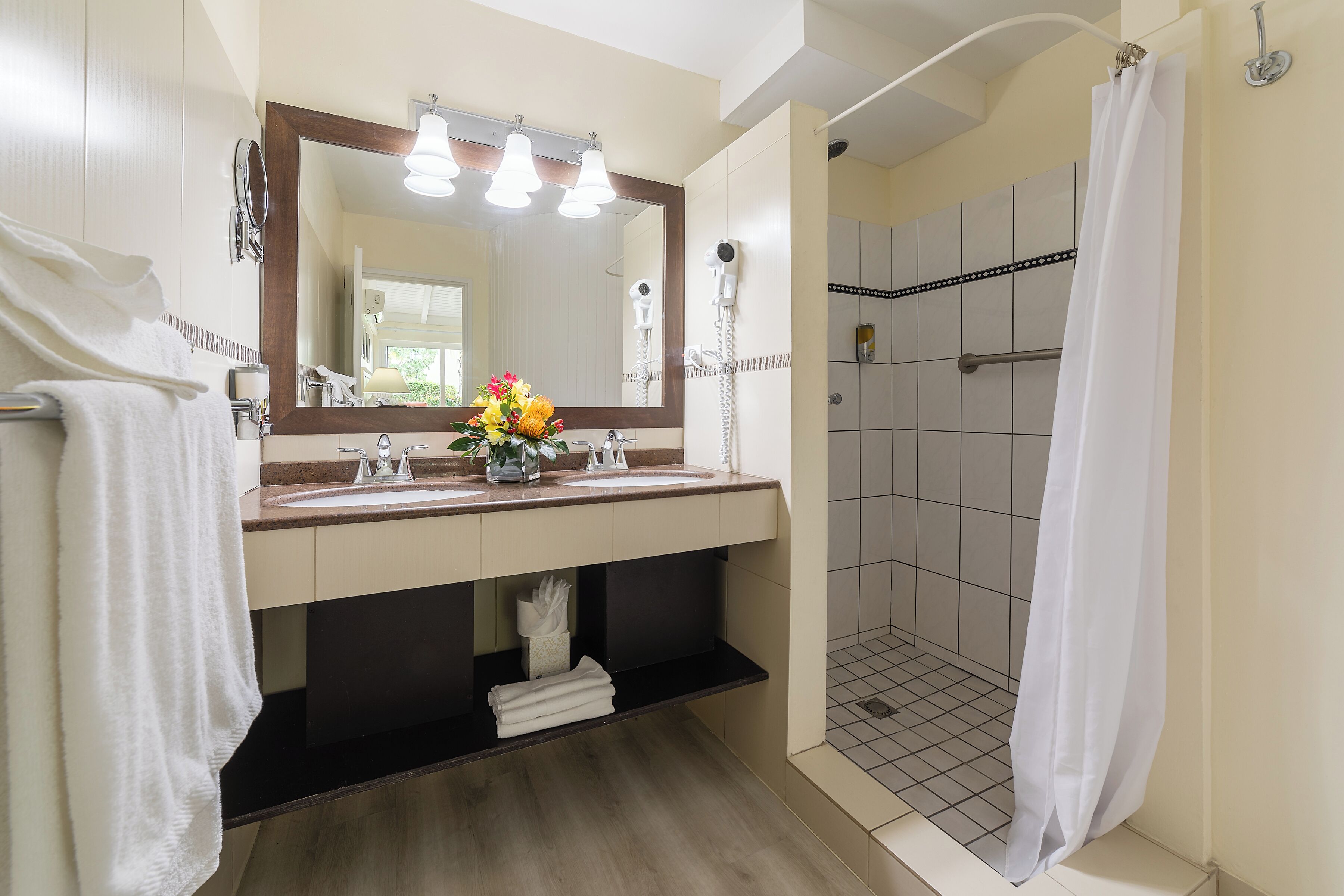 Ein Badezimmer mit einem großen Spiegel, zwei Waschbecken, einer Dusche und einem Handtuchhalter.