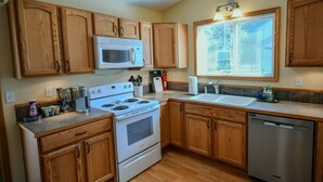 A modern kitchen with wooden cabinets, a stainless steel dishwasher, and a built-in microwave.