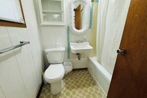 Bathroom features a toilet, sink, and shower area with a curtain.