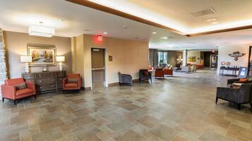 A spacious lobby with a herringbone tile floor, a reception desk, and seating areas.