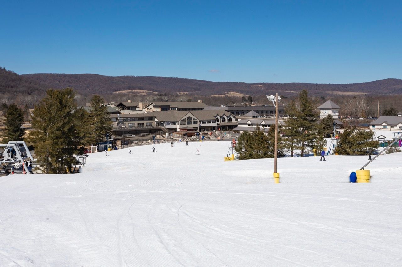 A ski resort with a large lodge, ski slopes, and a clear view of the surrounding mountains.