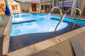 Une piscine intérieure avec un jacuzzi, un revêtement de sol carrelé et un panneau indiquant qu’il est interdit de plonger.