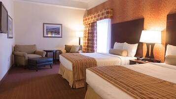 A hotel room with two beds, a sofa, a small table, and a TV.