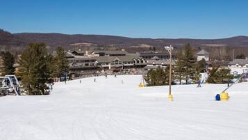 A ski resort with a large lodge, ski slopes, and a clear view of the surrounding mountains.