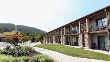 Un hotel a più piani con tetto piatto, balconi e un giardino antistante curato.