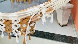 A modern interior with a hammock, dining tables, chairs, and a potted plant. - Pousada Lobo Guará (São João Batista do Glória)