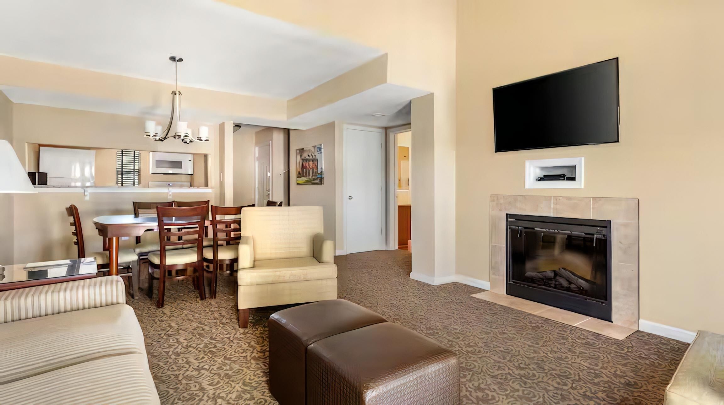 A hotel room with a living area, dining space, and a fireplace.