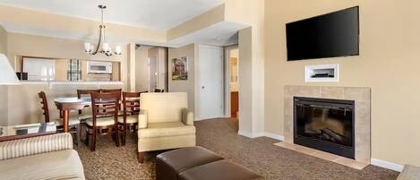 A hotel room with a living area, dining space, and a fireplace.