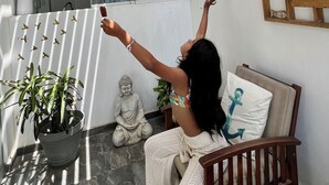 Une pièce avec un plafond en bois, une fenêtre, une statue de Bouddha et une chaise avec un coussin.