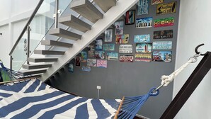 Un escalier avec un hamac et un mur décoré d’anciennes enseignes de planches de surf.